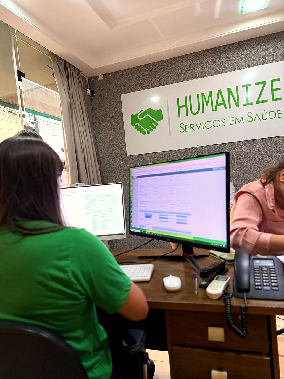 Profissional da Humanize registrando atendimento no sistema, sob a placa da marca